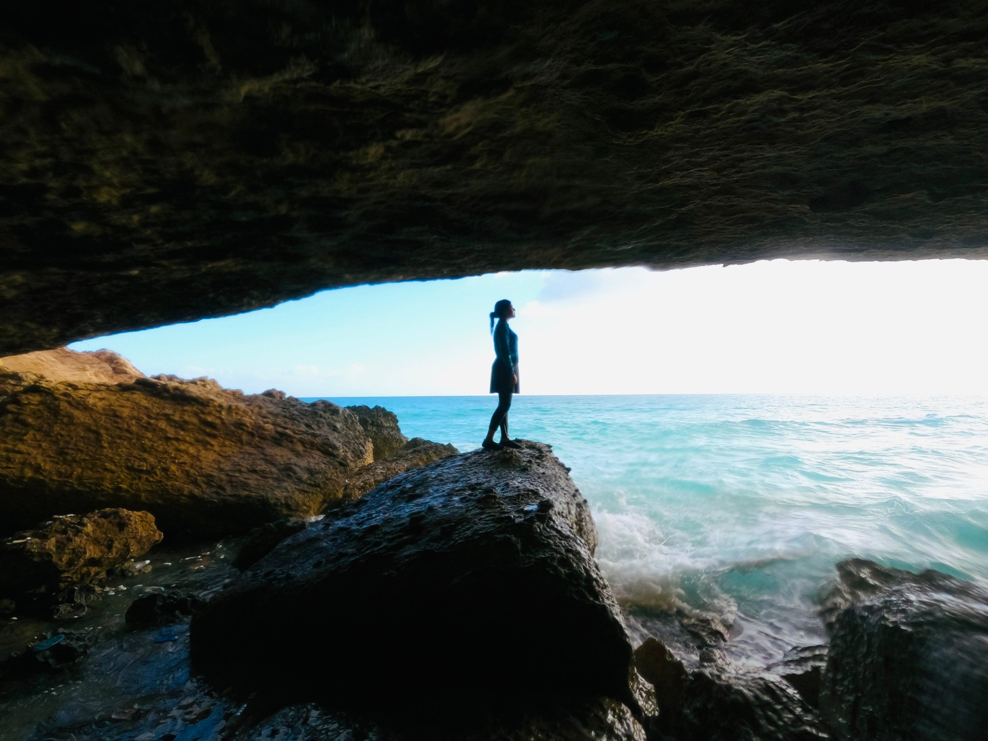 Person standing inside a Matahani cave looking out at the Mediterranean sea