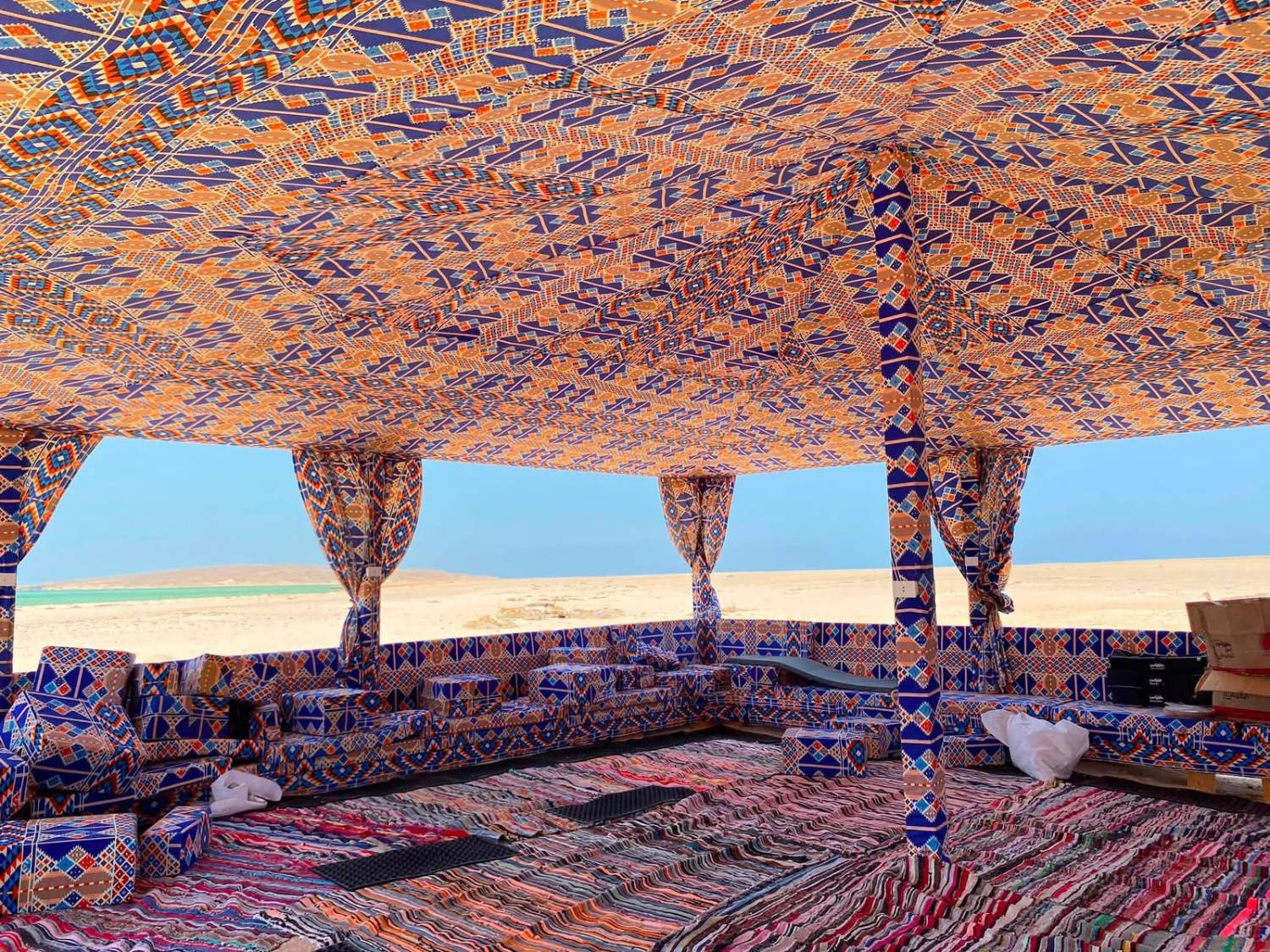 Bedouin-style camp tent interior with traditional colourful fabric, open to the sea view
