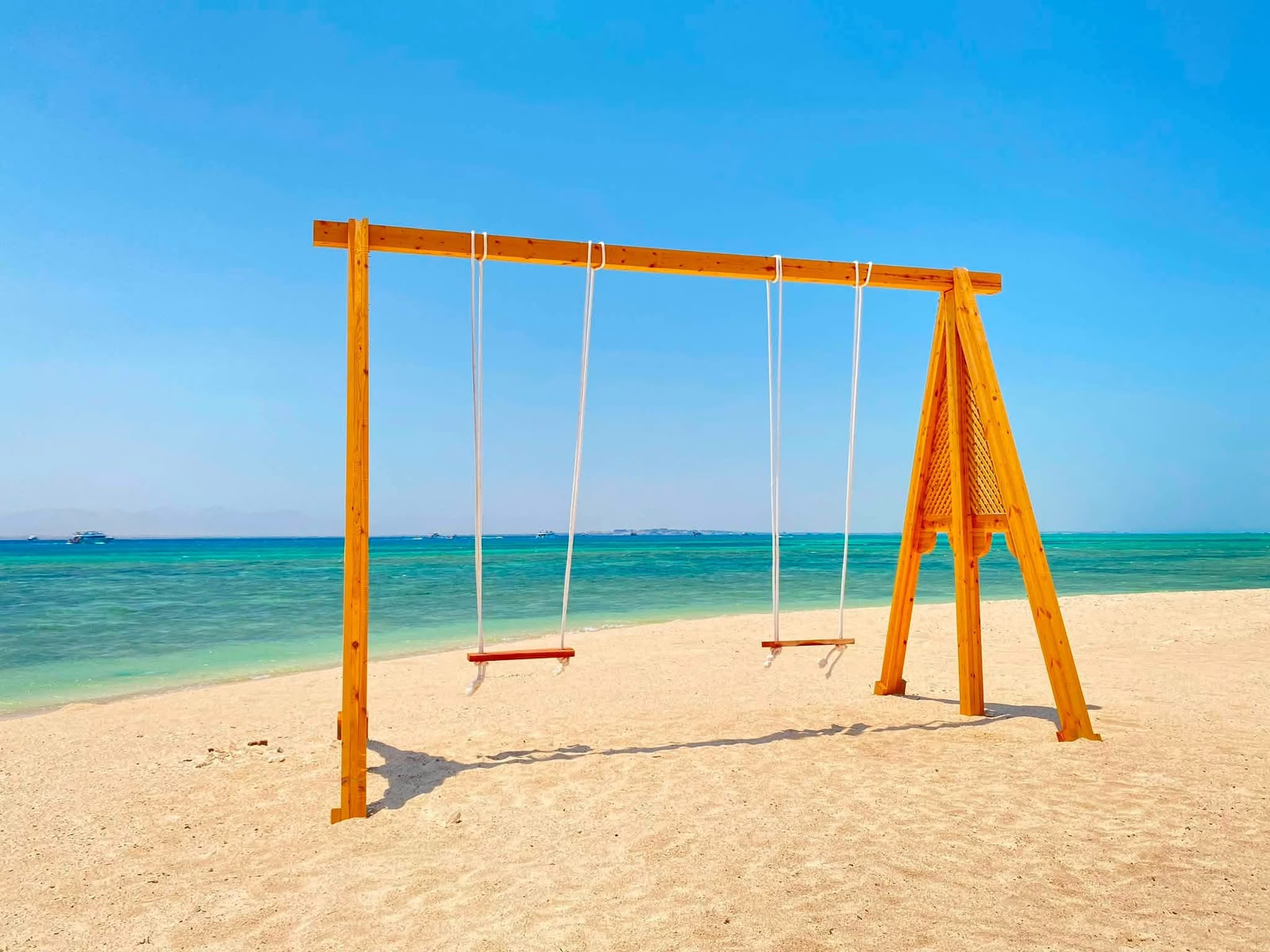 Wooden swings on a pristine white sand beach with turquoise Mediterranean water